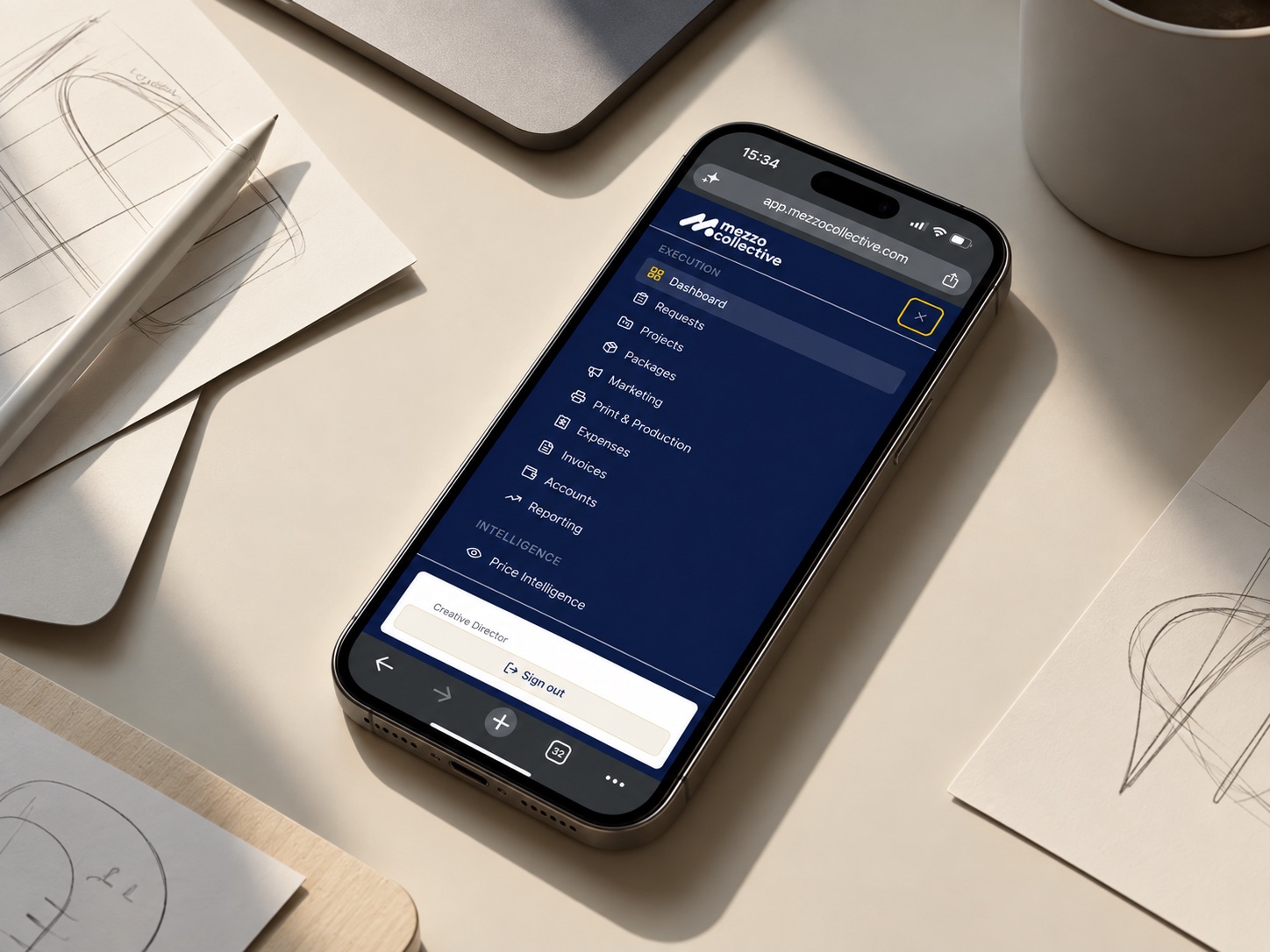 A phone on a desk showing the Mezzo Collective client platform, beside design sketches