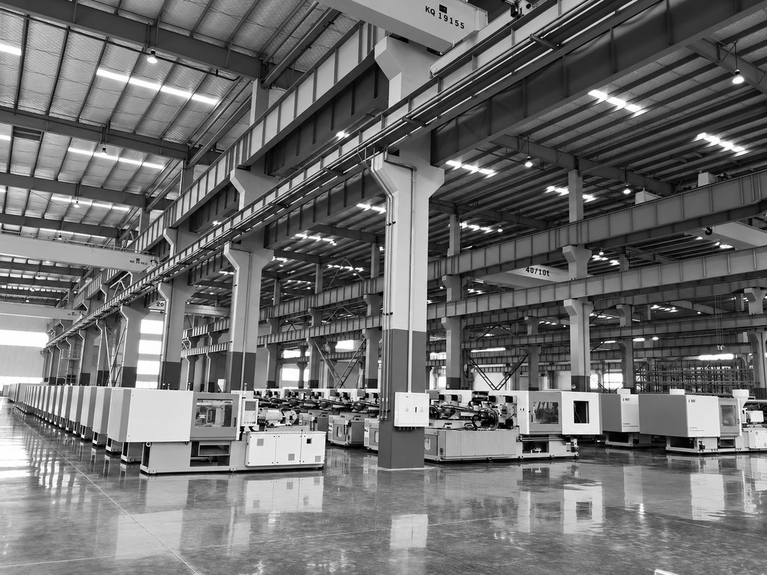 Rows of injection moulding machines running the length of a factory hall under overhead gantry cranes