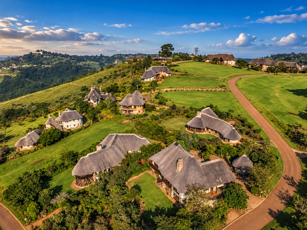 Aerial view of the Phezulu estate, thatched homes set across green hillside lawns