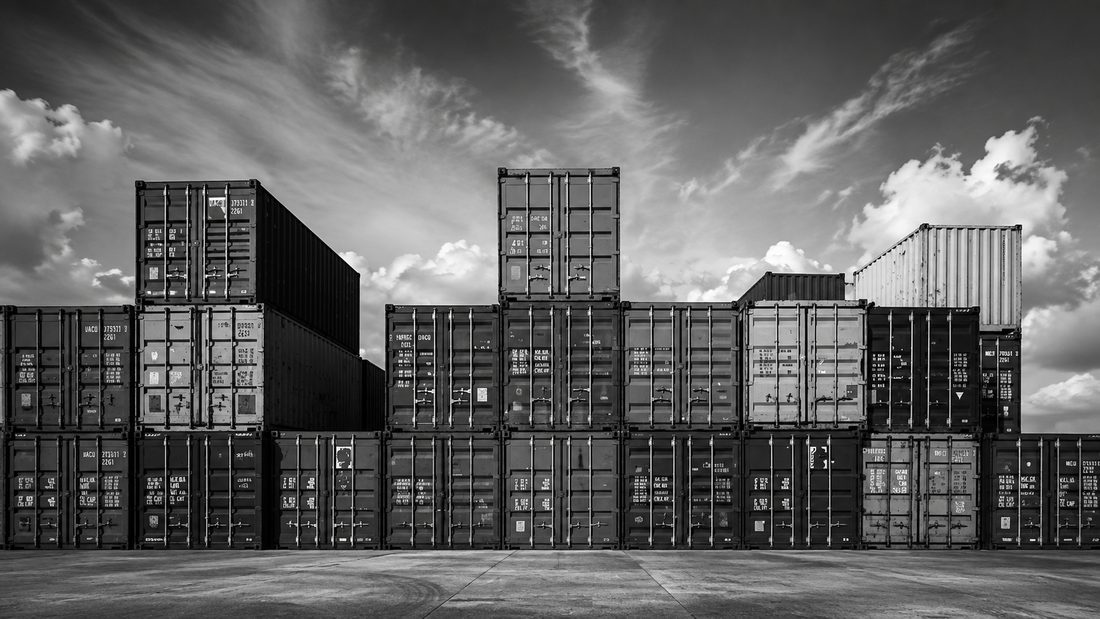 Shipping containers stacked several high in a yard under an open sky